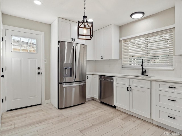 kitchen featuring light wood-style flooring, appliances with stainless steel finishes, white cabinetry, and a sink