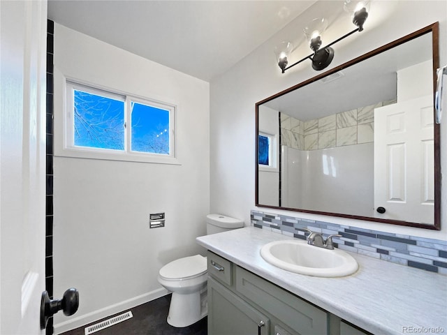 bathroom featuring toilet, walk in shower, backsplash, and vanity