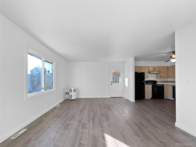 unfurnished living room with ceiling fan, a wealth of natural light, and light hardwood / wood-style floors