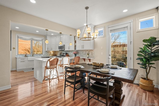 dining room with sink, an inviting chandelier, light wood-type flooring, and plenty of natural light