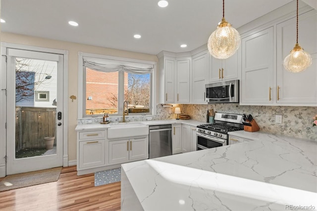 kitchen with stainless steel appliances, white cabinets, pendant lighting, and sink