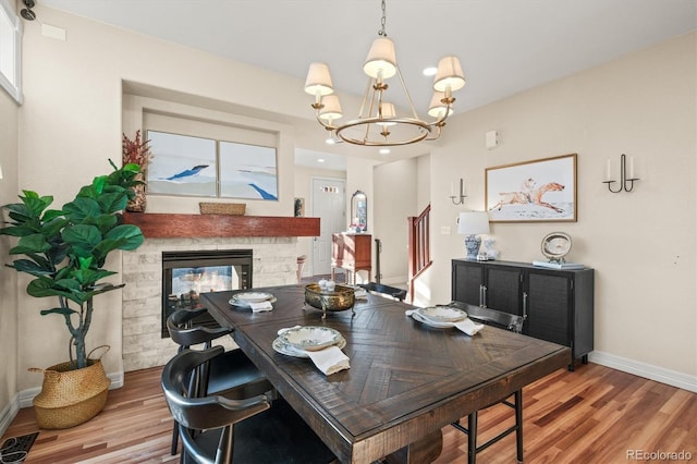 2801 W 23rd Ave, Denver, CO 80211 - dining area with baseboards, a notable chandelier, a glass covered fireplace, and light wood-type flooring