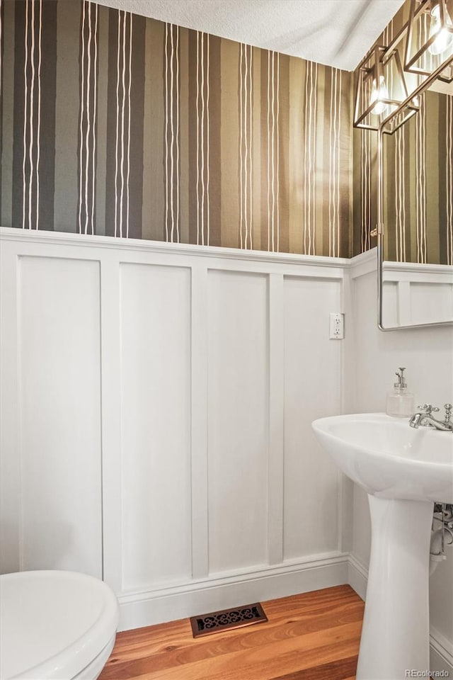 2801 W 23rd Ave, Denver, CO 80211 - half bathroom featuring toilet, visible vents, a decorative wall, a wainscoted wall, and wood finished floors