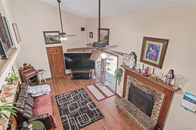 9400 W Burgundy Ave, Littleton, CO 80123 - living room with a ceiling fan, vaulted ceiling, wood finished floors, a fireplace with raised hearth, and a textured ceiling