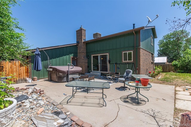 9400 W Burgundy Ave, Littleton, CO 80123 - rear view of house with a hot tub, a patio, a chimney, brick siding, and board and batten siding