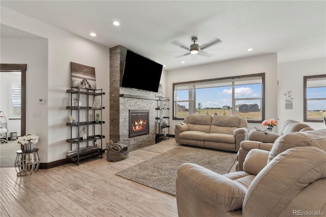 living area featuring a stone fireplace, recessed lighting, a ceiling fan, and light wood-style floors