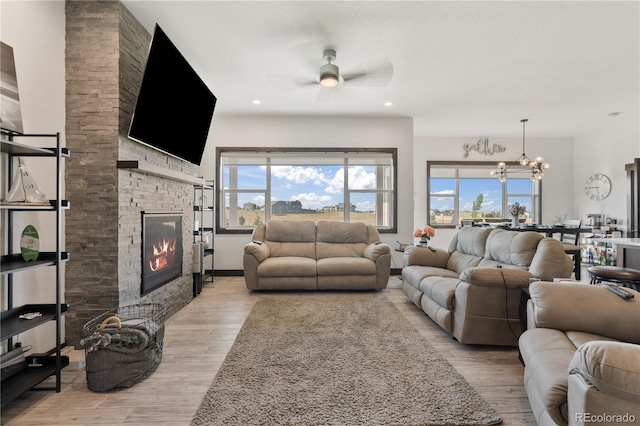 living room with ceiling fan with notable chandelier, a fireplace, wood finished floors, and recessed lighting