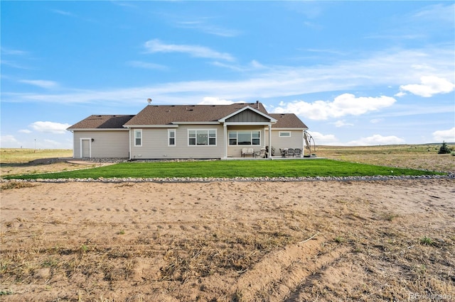 back of property featuring a lawn, a patio area, and board and batten siding