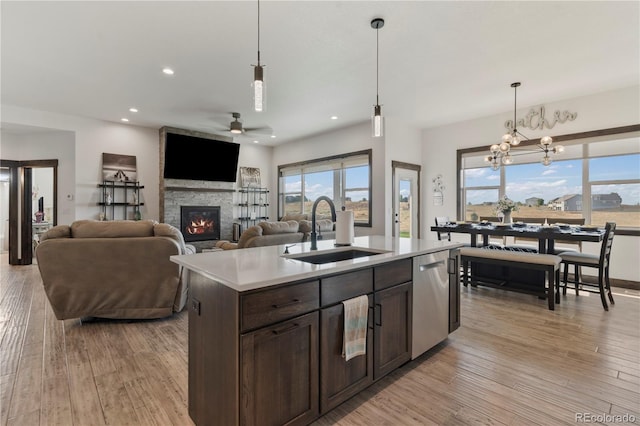 kitchen with light wood-style floors, a sink, stainless steel dishwasher, and dark brown cabinets