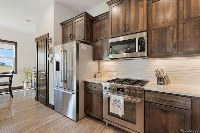 kitchen featuring light wood finished floors, light countertops, appliances with stainless steel finishes, and backsplash