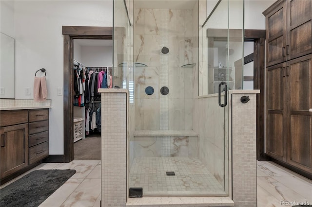 bathroom with a walk in closet, a shower stall, and vanity