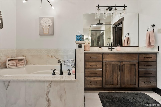 bathroom featuring walk in shower, a bath, and vanity