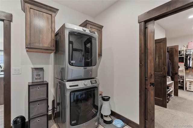 washroom featuring light carpet, cabinet space, and stacked washer / dryer