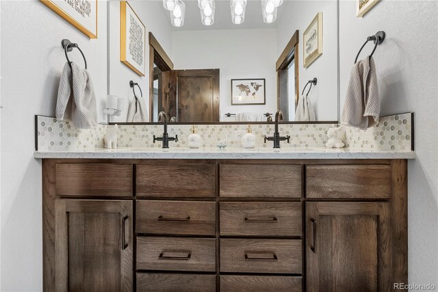 full bath with a sink, decorative backsplash, and double vanity