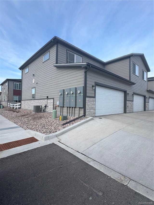 1353 Reynolds St Unit 5A, Fort Lupton, CO 80621 - view of side of home with driveway, mail area, stone siding, and central air condition unit