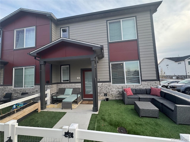 1353 Reynolds St Unit 5A, Fort Lupton, CO 80621 - view of front of house featuring an outdoor living space, a fenced front yard, stone siding, and a patio area