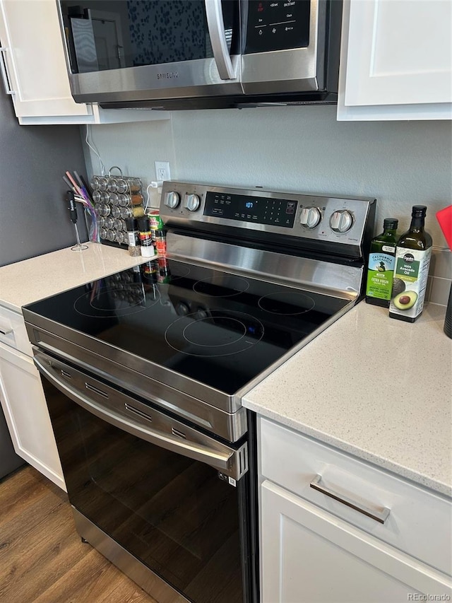 1353 Reynolds St Unit 5A, Fort Lupton, CO 80621 - kitchen featuring stainless steel appliances, white cabinets, wood finished floors, and light stone countertops
