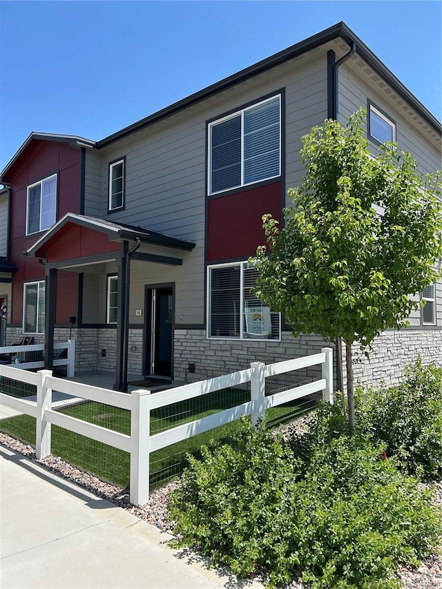 1353 Reynolds St Unit 5A, Fort Lupton, CO 80621 - view of front of property with a fenced front yard, covered porch, and stone siding