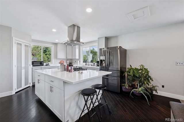 15528 Nancy Ave, Fort Lupton, CO 80621 - kitchen with stainless steel appliances, island exhaust hood, a breakfast bar area, a kitchen island, and light countertops