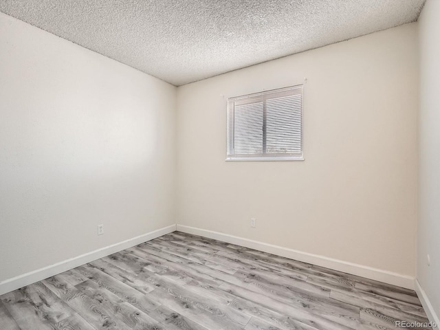 unfurnished room with a textured ceiling and light wood-type flooring