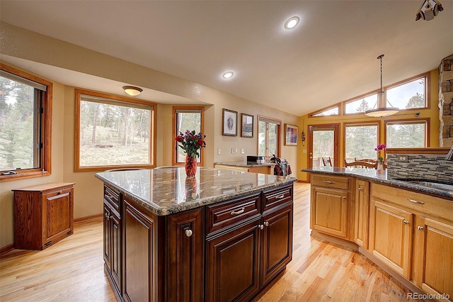 199 Elk Horn Ct, Bailey, CO 80421 - kitchen featuring light wood-style flooring, hanging light fixtures, dark stone countertops, a sink, and vaulted ceiling