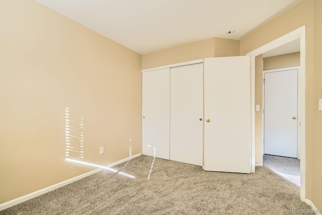 unfurnished bedroom with a closet and light colored carpet