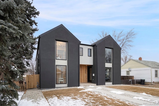 contemporary home with fence and stucco siding