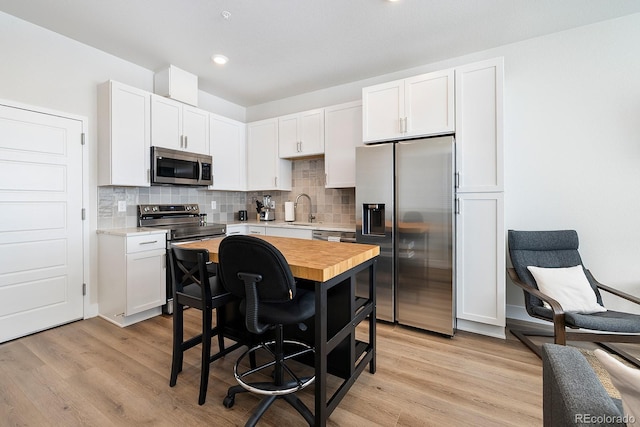 kitchen featuring sink, wooden counters, white cabinets, stainless steel appliances, and light wood-type flooring