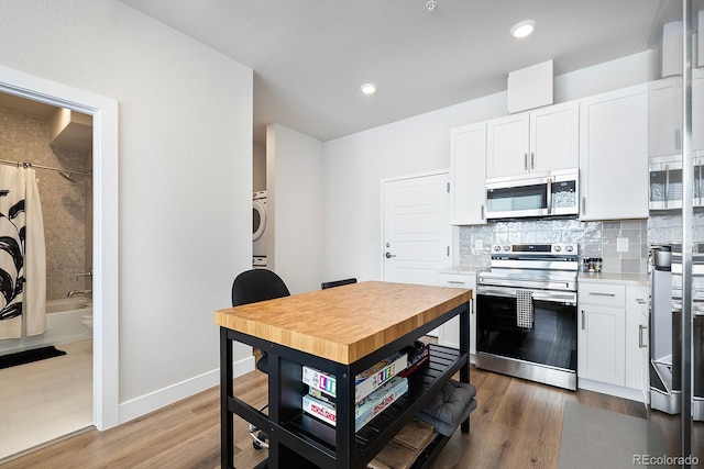 kitchen with dark hardwood / wood-style floors, washer / clothes dryer, white cabinets, decorative backsplash, and stainless steel appliances