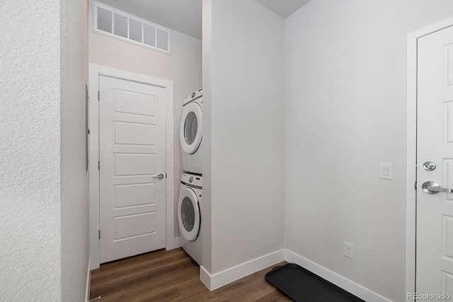 clothes washing area with dark hardwood / wood-style flooring and stacked washer / drying machine