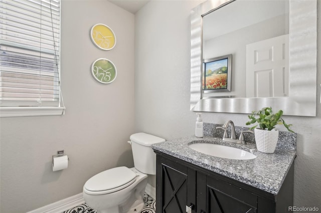 bathroom with toilet, vanity, and baseboards