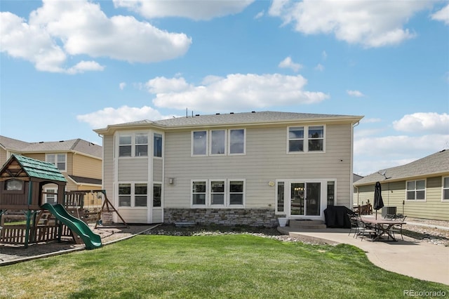 back of house featuring a lawn, a patio area, a playground, and stone siding