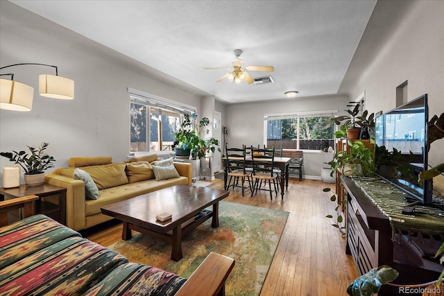 living room featuring hardwood / wood-style flooring, ceiling fan, visible vents, and a wealth of natural light