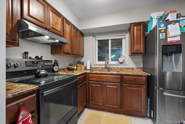 kitchen featuring stainless steel fridge, stone countertops, under cabinet range hood, black range with electric cooktop, and a sink