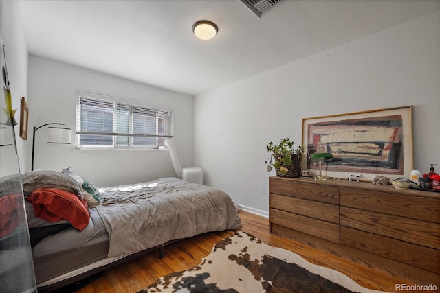 bedroom with wood finished floors, visible vents, and baseboards