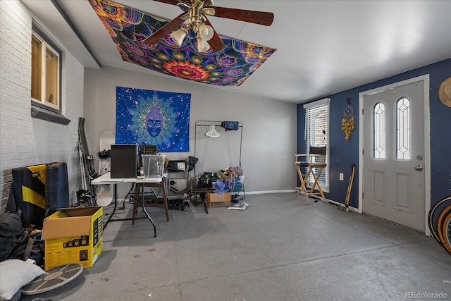 office space featuring concrete flooring, ceiling fan, and baseboards