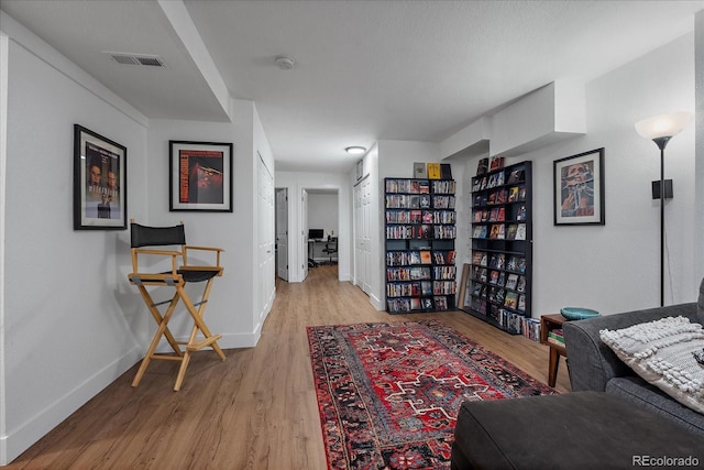 living area with visible vents, baseboards, and wood finished floors