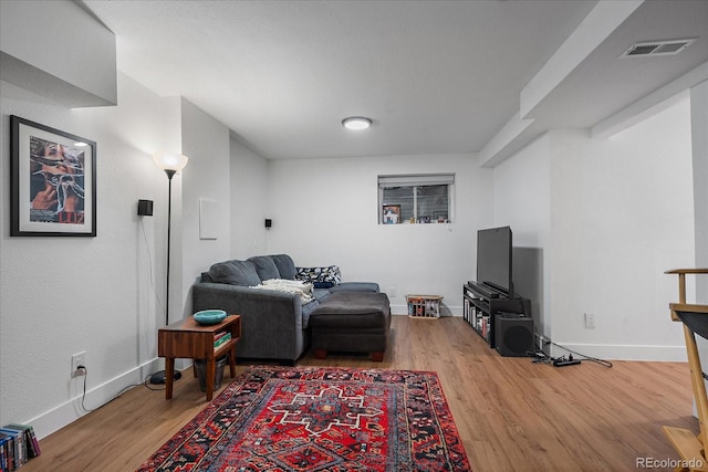 living room featuring visible vents, baseboards, and wood finished floors