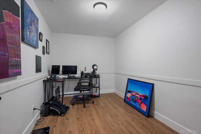 office area with a textured ceiling, baseboards, and wood finished floors