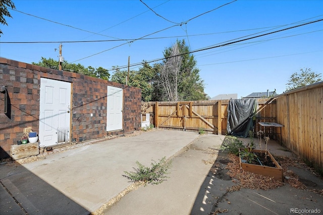 view of patio / terrace with a gate, a garden, fence, and an outdoor structure