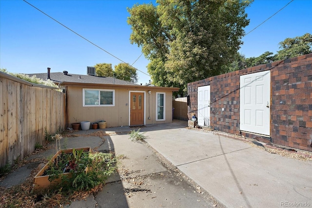 view of front of house featuring a vegetable garden, fence, a patio, and an outbuilding