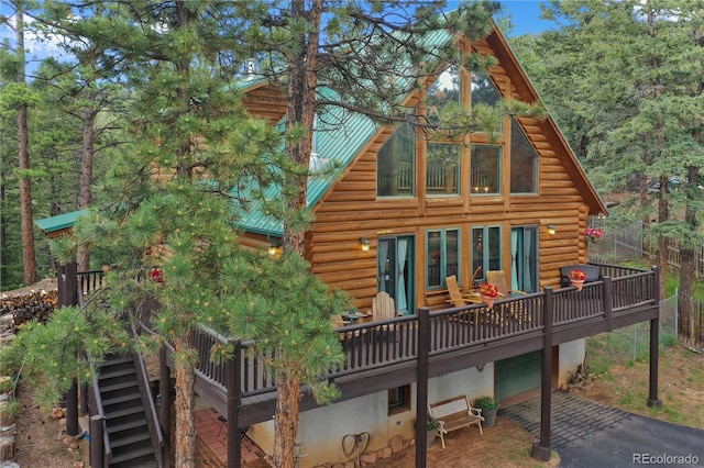 2255 Spruce Rd, Woodland Park, CO 80863 - rear view of house featuring log siding, driveway, a garage, a metal roof, and a wooden deck