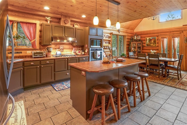 2255 Spruce Rd, Woodland Park, CO 80863 - kitchen with rustic walls, appliances with stainless steel finishes, wood ceiling, under cabinet range hood, and a center island