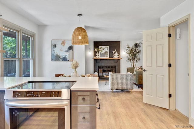 10016 Teton Ct, Lone Tree, CO 80124 - kitchen with stainless steel electric stove, light wood-type flooring, light countertops, and a brick fireplace