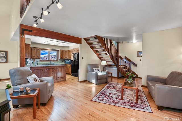 living room with sink, beamed ceiling, and light wood-type flooring