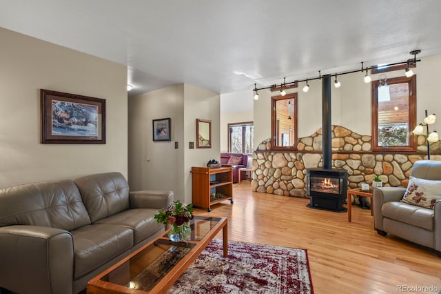 living room featuring wood-type flooring, rail lighting, and a wood stove