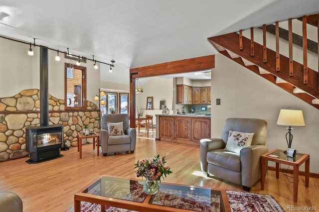 living room featuring track lighting, light hardwood / wood-style floors, and a wood stove