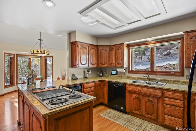 kitchen featuring kitchen peninsula, light wood-type flooring, sink, decorative light fixtures, and dishwasher