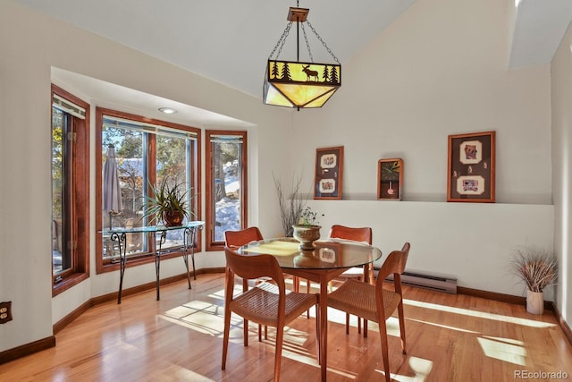 dining space with lofted ceiling, light hardwood / wood-style floors, and a baseboard heating unit