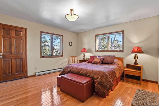 bedroom with multiple windows, light wood-type flooring, and baseboard heating